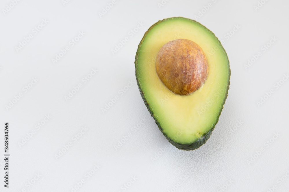Cut half of avocado with seed. Top view, closeup. Isolated object on white background. Fresh food or healthy diet concept
