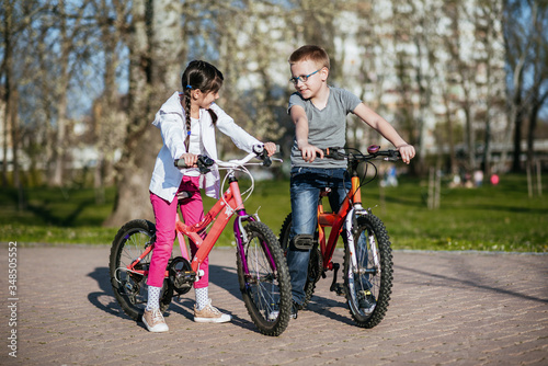 Kids riding bikes in a park. Children enjoy bike ride in the city. Brother and sister friends forever. 