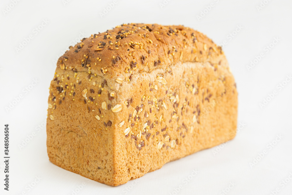 Fresh brick form bread baking at home. Crunchy whole loaf with cereals, oats, seeds isolated on white background. Studio shot. Selective focus. Side view. Homemade food and nutrition concept Fresh brick form bread baking at home. Crunchy whole loaf with cereals, oats, seeds isolated on white background. Studio shot. Selective focus. Side view. Homemade food and nutrition concept