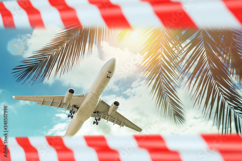 Plane in sky closed warning tape. Quarantine, canceled flight and deferred vacation concept