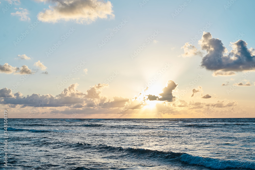Sunset at the sea. Turquoise water in the ocean in the evening. Yellow sky with small clouds and blue waves at sandy beach at the seaside. Paradise resort landscape.Tropical resort travel picture. Sunset at the sea. Turquoise water in the ocean in the evening. Yellow sky with small clouds and blue waves at sandy beach at the seaside. Paradise resort landscape.Tropical resort travel picture.