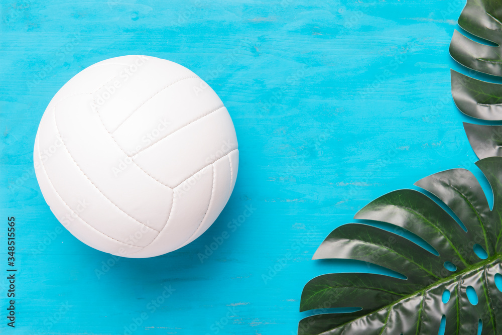 Two tropical monstera leaves and ball on blue wooden background