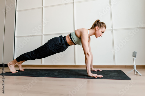 woman doing sport workout at home via online live training on phone