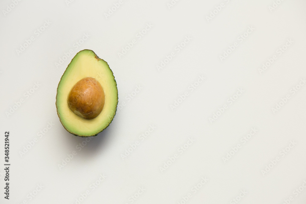 Single cut half of avocado with seed. Top view, closeup, copy space. Isolated object on white background. Fresh food or advertising