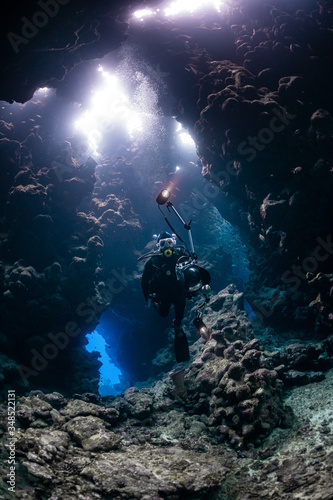 typical underwater cave in a red sea reef with an underwater photographer diver © Subphoto