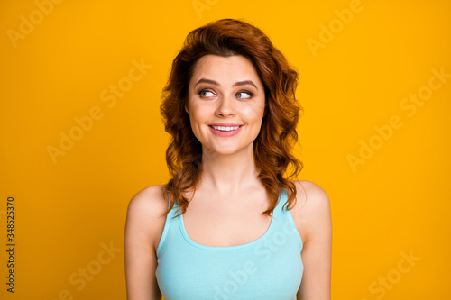 Closeup photo of pretty curly foxy lady cheerful person good mood white teeth smile look interested side empty space wear teal casual singlet isolated vibrant yellow color background