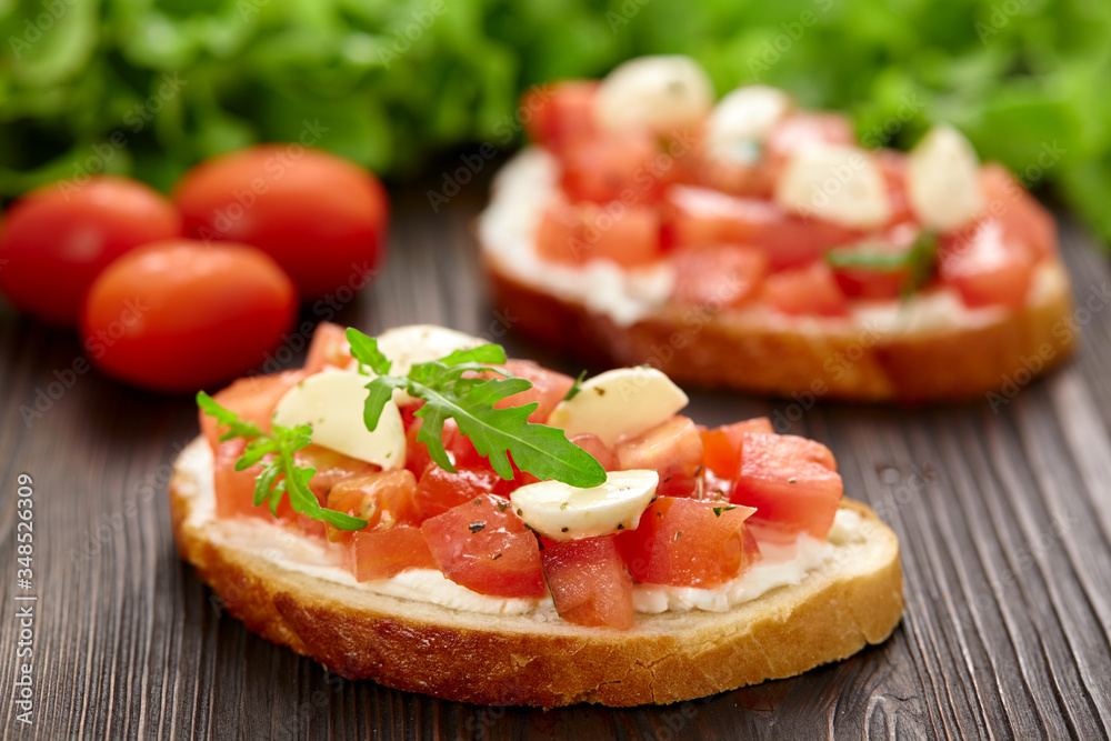 Homemade bruschetta with tomatoes and mozzarella on a wooden board.