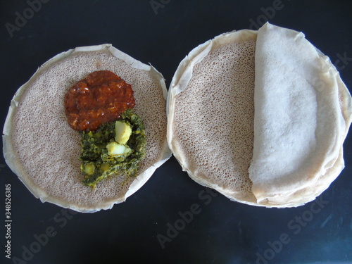 Asmara, Eritrea - 08/05/2020: Ethiopian and Eritrean food, assortment of main dishes. Injera is a sourdough flatbread made from teff flour. It is the national dish of Ethiopia, Eritrea.