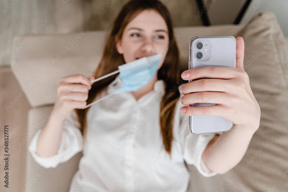 woman at home on couch wearing mask making selfie on phone woman at home on couch wearing mask making selfie on phone