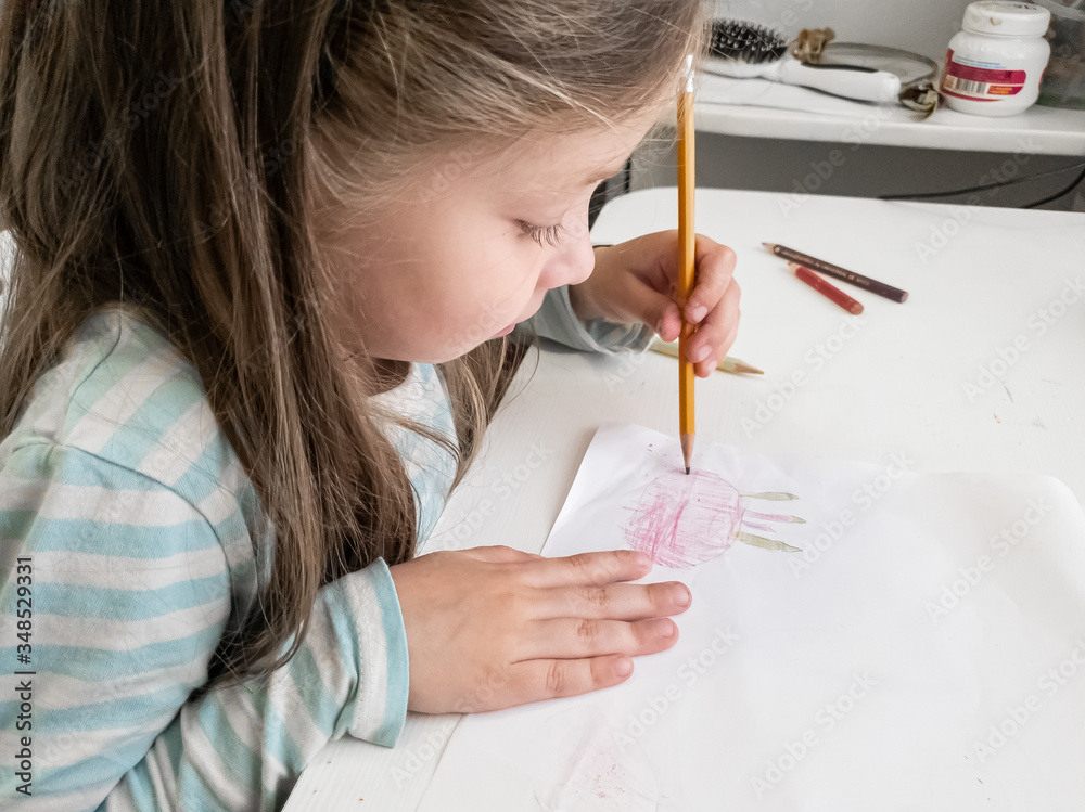 a little girl draws with colored pencils with her left hand, children's joint creativity a little girl draws with colored pencils with her left hand, children's joint creativity