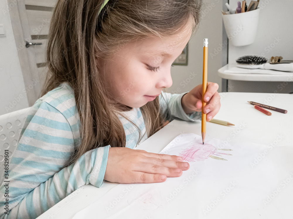 a little girl draws with colored pencils with her left hand, children's joint creativity a little girl draws with colored pencils with her left hand, children's joint creativity