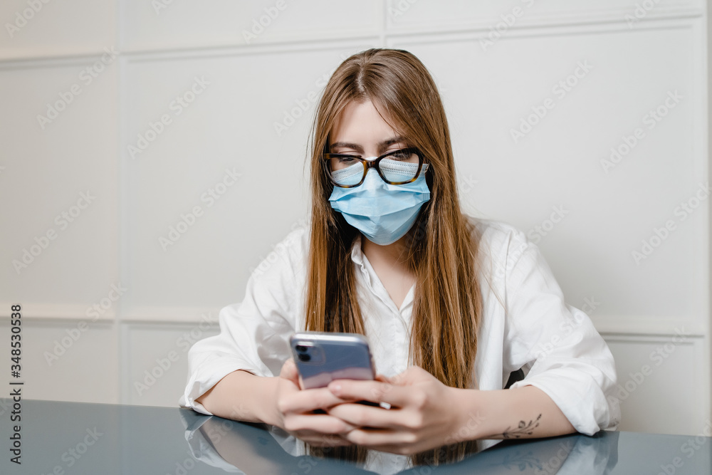woman at home office wearing mask and using phone