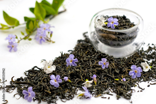 Dry green tea herbs with flowers on white background.
