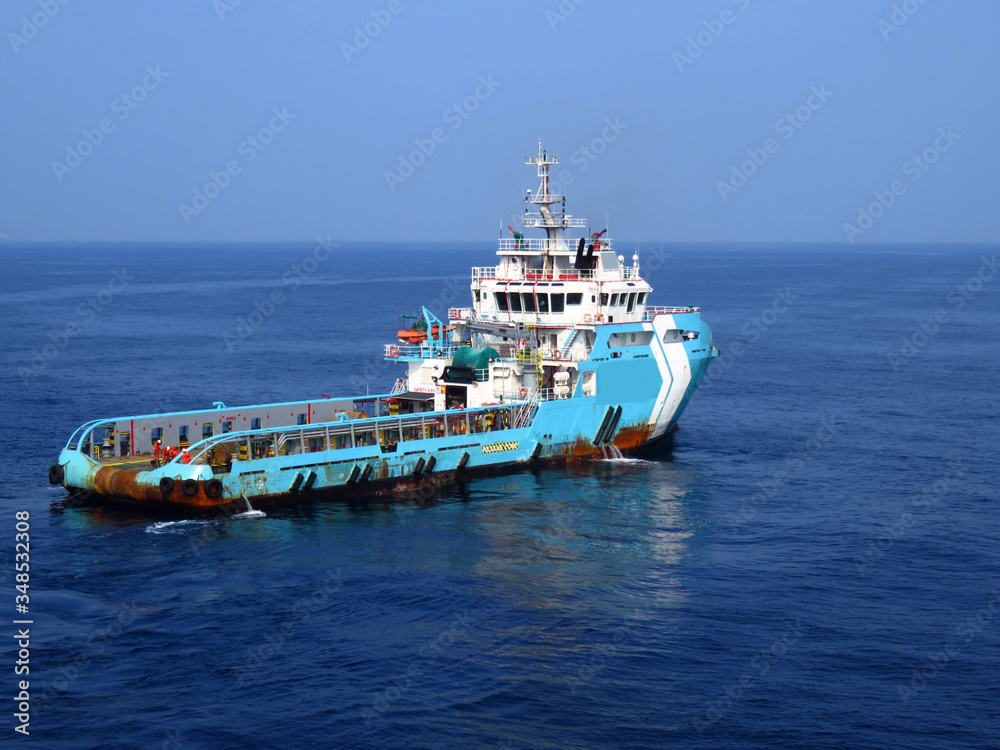 Supply boat (crew boat) transfer worker and cargo by personnel basket from platform to supply boat of oil and gas industry.