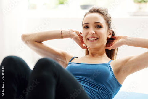 Fit woman doing sit ups at home on the floor