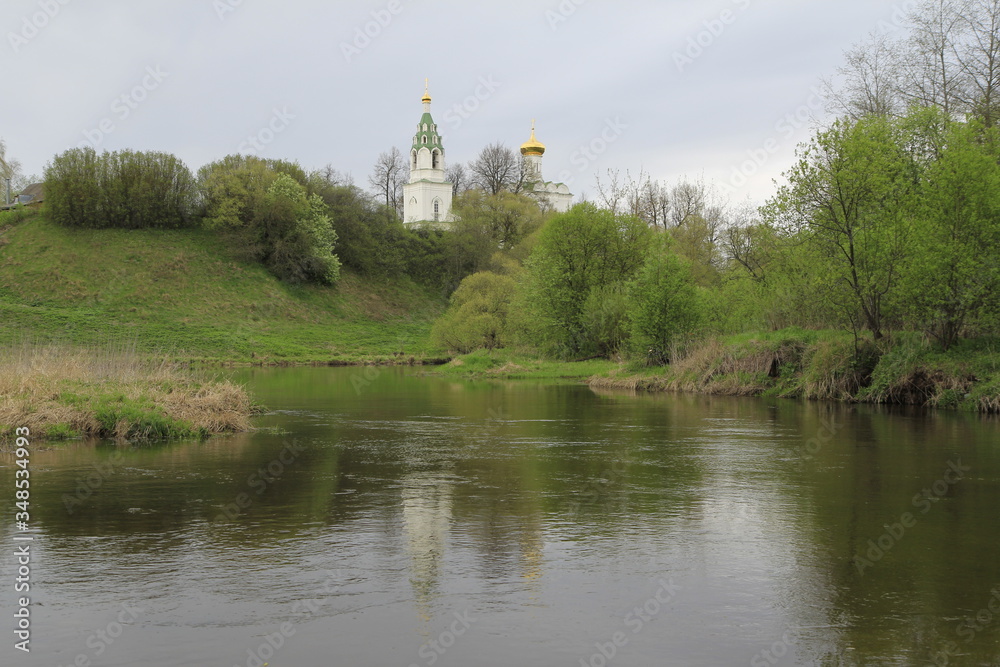 Spring landscape with river, gray sky and small church domes Spring landscape with river, gray sky and small church domes