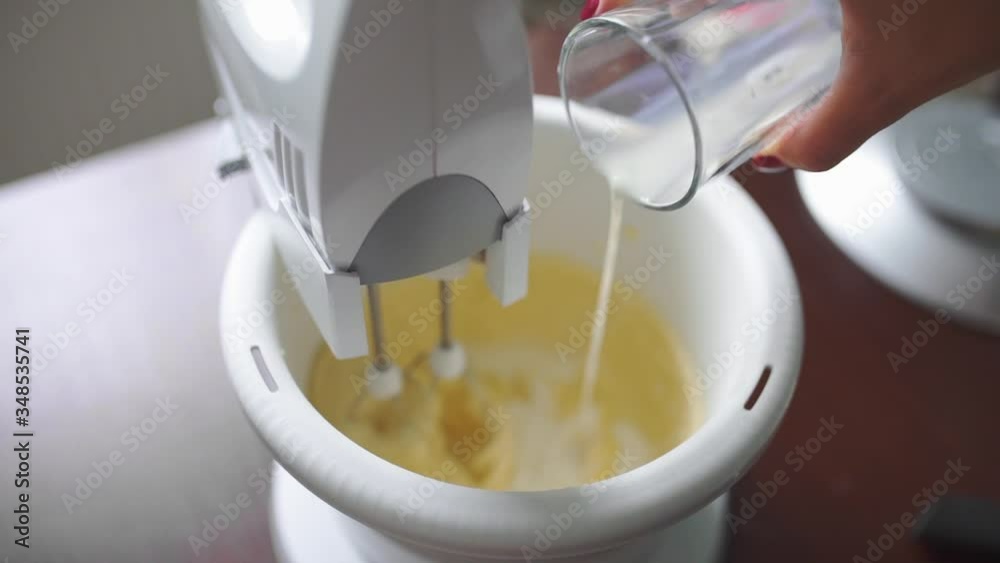 baker adds milk to the mixer cup baker adds milk to the mixer cup