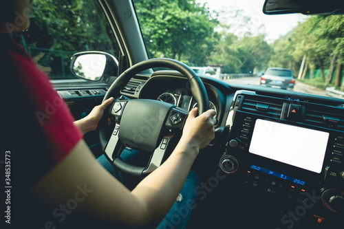 People hands holding steering wheel while driving car on city road