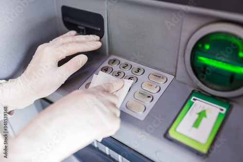 Canvas Print Hands in surgical rubber gloves sanitizing atm machine buttons with wet wipe, covid-19 prevention