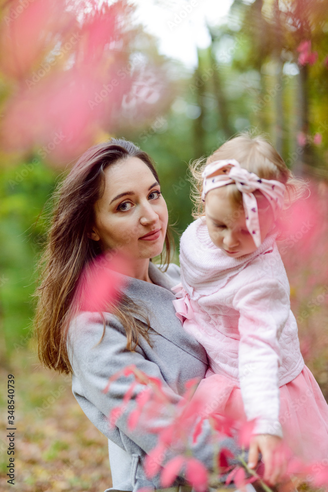 Mother holds daughter in her arms in the park on a sunny day. Autumn day. Mother holds daughter in her arms in the park on a sunny day. Autumn day.
