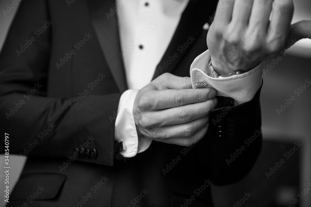 the groom buttoning the cufflinks of his shirt on the wedding day