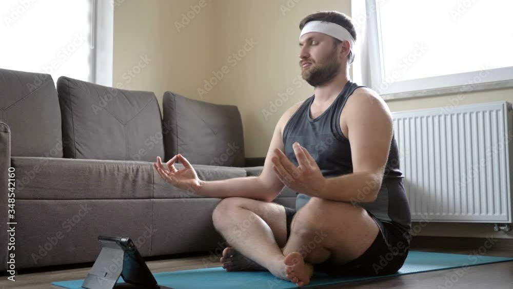 Young man practices yoga at home. Laptop is next to him. Online sport. Sport in quarantine at home. Young man practices yoga at home. Laptop is next to him. Online sport. Sport in quarantine at home.