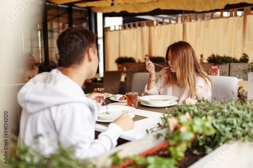 Beautiful cheerful girl relaxes on the summer terrace of the restaurant with food and drinks. Relaxation on the summer terrace on a summer sunny day