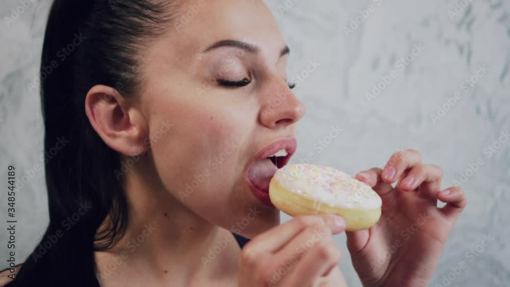 Junk food. Young beautiful woman bites off a piece of a donut, close-up. Junk food. Young beautiful woman bites off a piece of a donut, close-up.