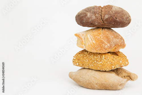 Pile of four wheat and rye breads with cereals. Fresh homemade loafs and pastry isolated on white background. Studio shot. Side view. Cooking and baking at home concept