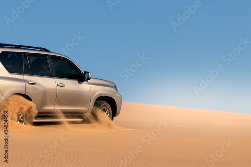 Close up of a golden car stuck in the sand in the Namib desert. © Yuliia Lakeienko