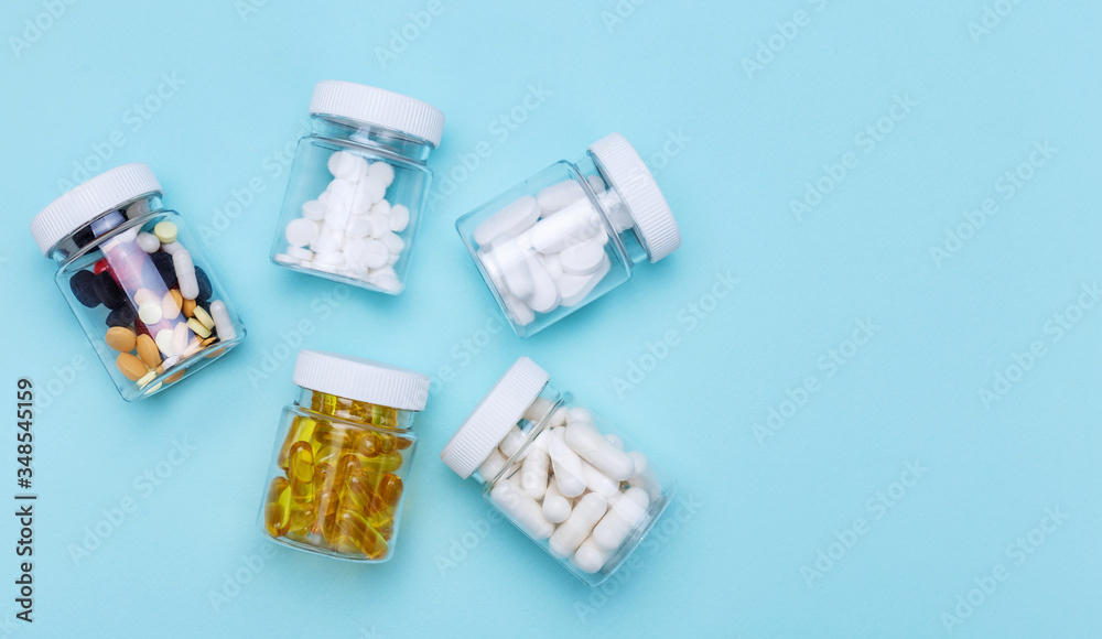 Five packs with various pills on a blue background. Health concept. Top view with copy space.