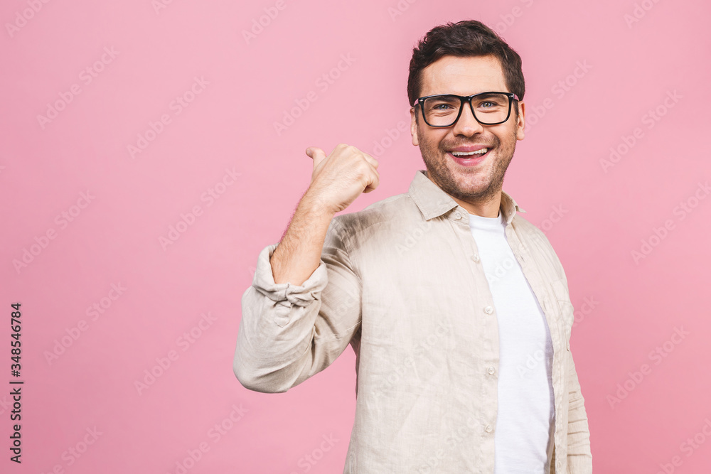 Smiling young man isolated on pink background. Stylish man wearing glasses, looking at camera and pointing finger. Smiling young man isolated on pink background. Stylish man wearing glasses, looking at camera and pointing finger.
