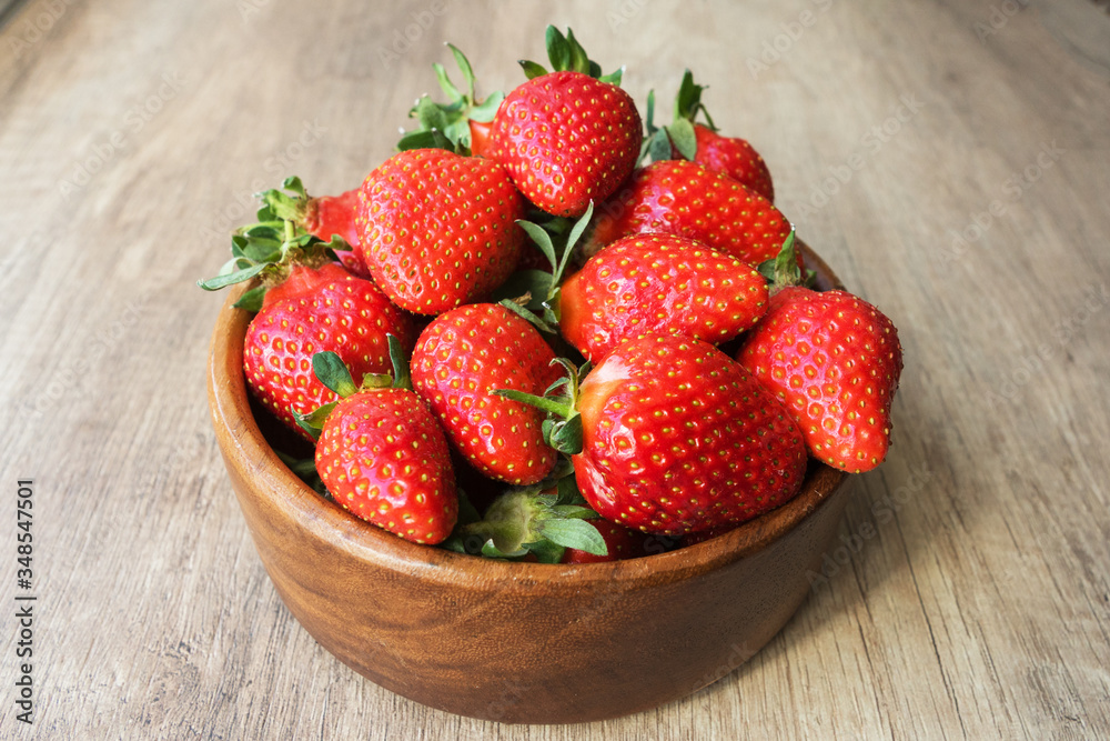 close up image of yummy delicious big red strawberry lie in round wooden plate on light wooden background, antioxidant nutrition, healthy food concept close up image of yummy delicious big red strawberry lie in round wooden plate on light wooden background, antioxidant nutrition, healthy food concept