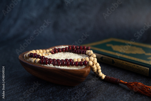 ZAKAT donation for Muslim according to religious principles during the Ramadan month, concept: rice grain in bow and rosary on black background