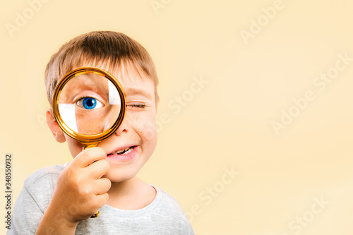 Child see through magnifying glass on the color yellow backgrounds. Big kid eye photo
