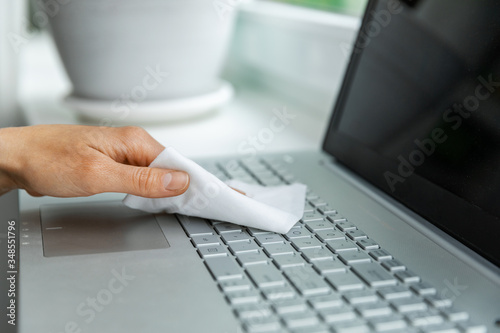 electronics disinfection and hygiene - hand cleaning laptop keyboard with antibacterial wet wipe