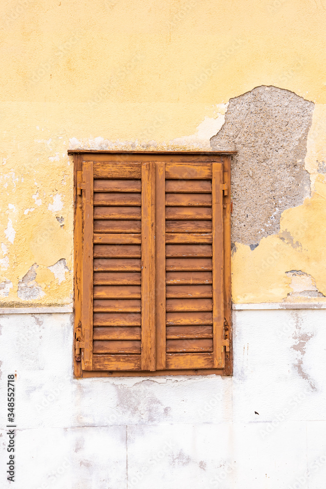 Eine alte Hausmauer und Fenster mit braunem Holz Fensterläden als Hintergrund