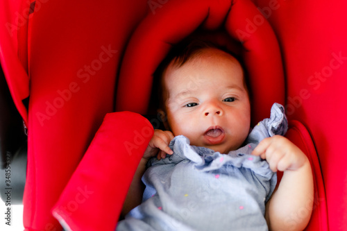 Newborn baby boy sleeping in modern car seat. New born child traveling by car. Child safety on the road. Safe way to travel with young kids. Fastened seat belts in a vehicle. Trip with an infant.