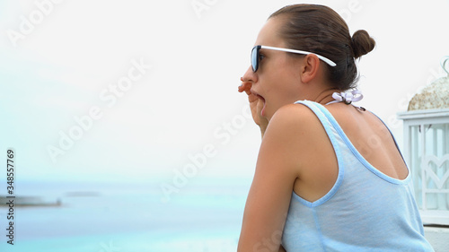 Shocked young woman looking at sometning from terrace by the sea 