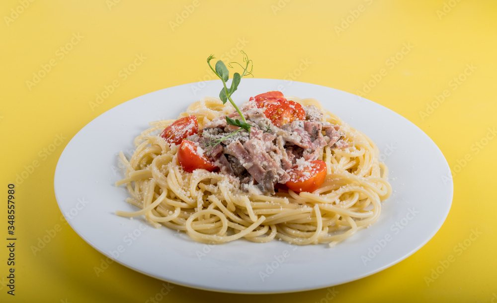 Spaghetti cooked pasta with ingredients on a yellow background. Colorful top and closeup view
