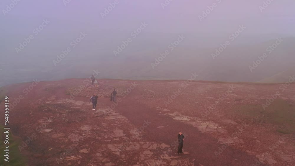 Hikers and visitors reach Brecon mountain peak of Pen-Y-Fan during foggy day, aerial drone shot Hikers and visitors reach Brecon mountain peak of Pen-Y-Fan during foggy day, aerial drone shot