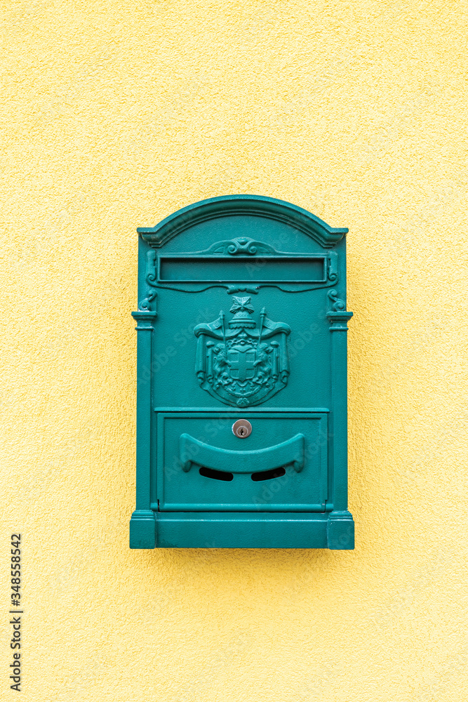 Gelbe Hausmauer mit einem grünen Postkasten als Hintergrund