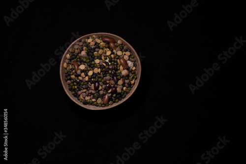 Top down image of a bowl of Indian mixed pulses in a dark copy space background. Food and product photography.