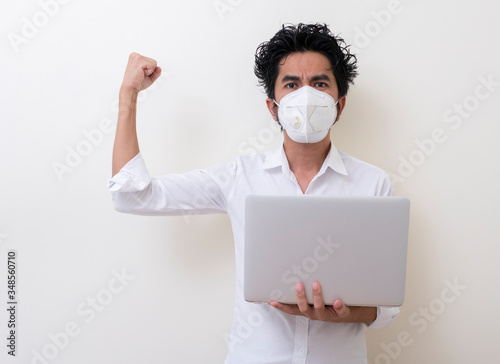 Business man in medical face mask works on laptop at home