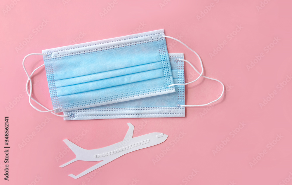 Plane model and face medical masks on a pink background . Plane model and face medical masks on a pink background .