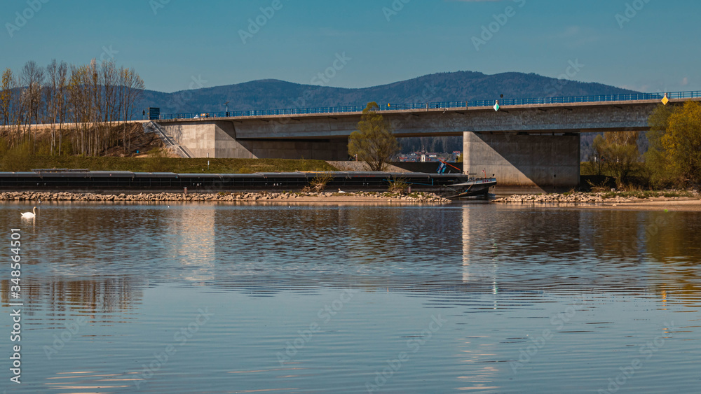 Beautiful spring view with reflections and a freight ship near Mettenufer, Danube, Bavaria, Germany
