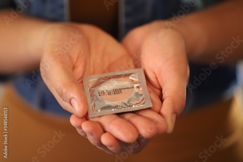 Focus hand,Yong woman use condoms before having sex every time to prevent AIDS.
