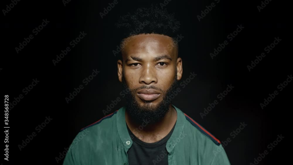 Young african man looking serious. African man with beard looking at camera on black background.
Young african man looking serious. African man with beard looking at camera on black background.
