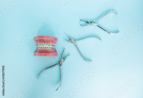 Metal braces for teeth and tools for correction of brace systems. Dental tools for the orthodontist. Dental instruments on a blue background in a dental clinic. photo