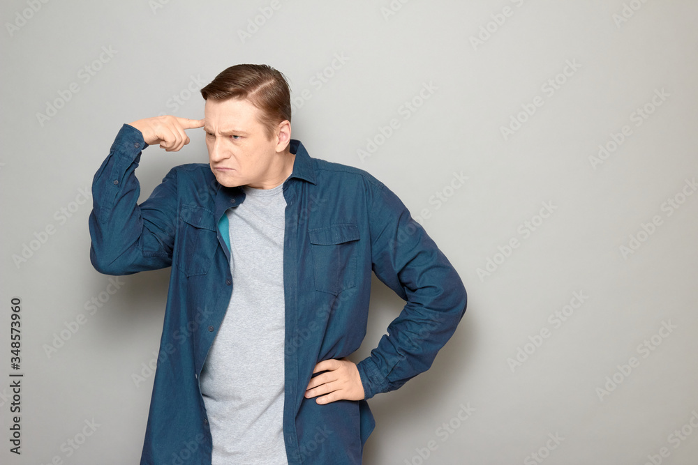 Portrait of funny thoughtful man touching head with finger and thinking hard Portrait of funny thoughtful man touching head with finger and thinking hard